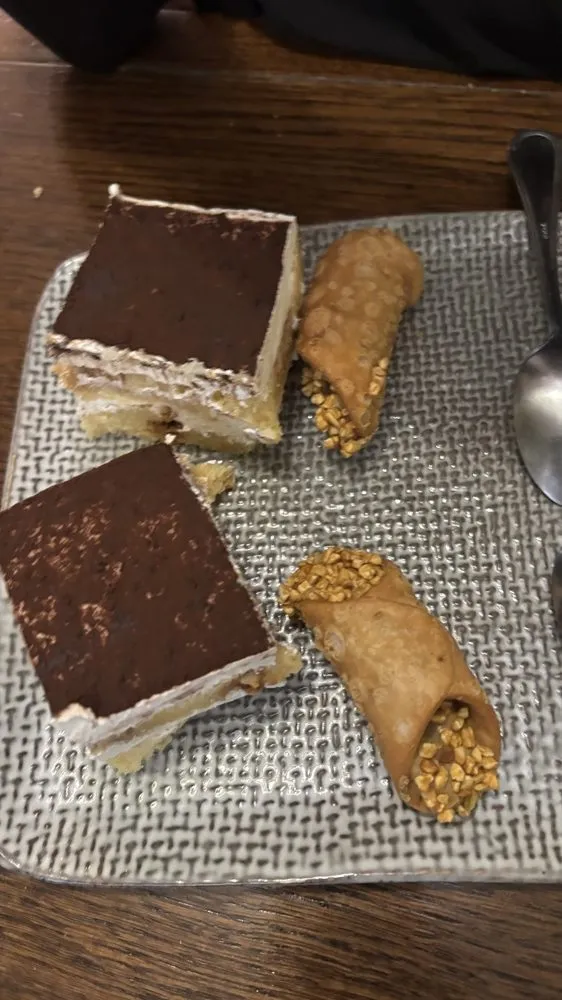 Parts de tiramisù et cannoli siciliens sur un plateau